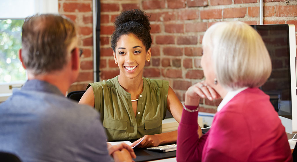 Three people talking at a desk.