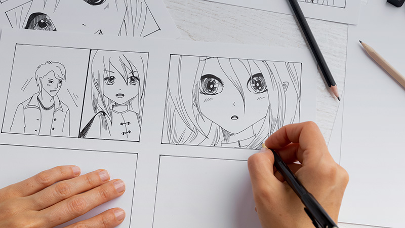 Hands holding pens while drawing anime
