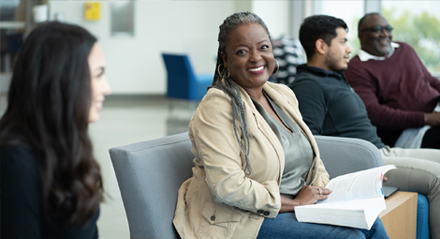 African American student with book on her lap with other students in the UHD welcome center