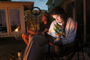 two people sitting in camping chairs outside in urban environment