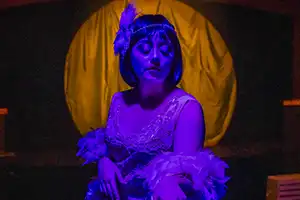 female actress dressed as a flapper under a purple light