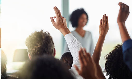Ask me anything - a raised hand in a room of people