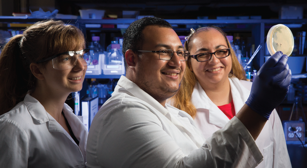 Image of three science students examining a specimen