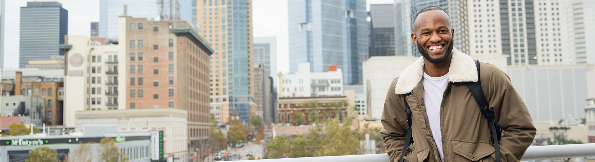 UHD Student standing on UHD deck with view of Houston Downtown