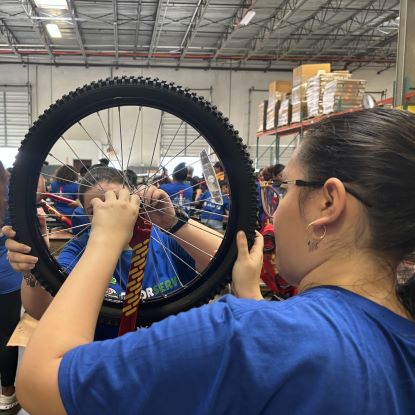 Two UHD volunteers work on the wheel of a bicycle.