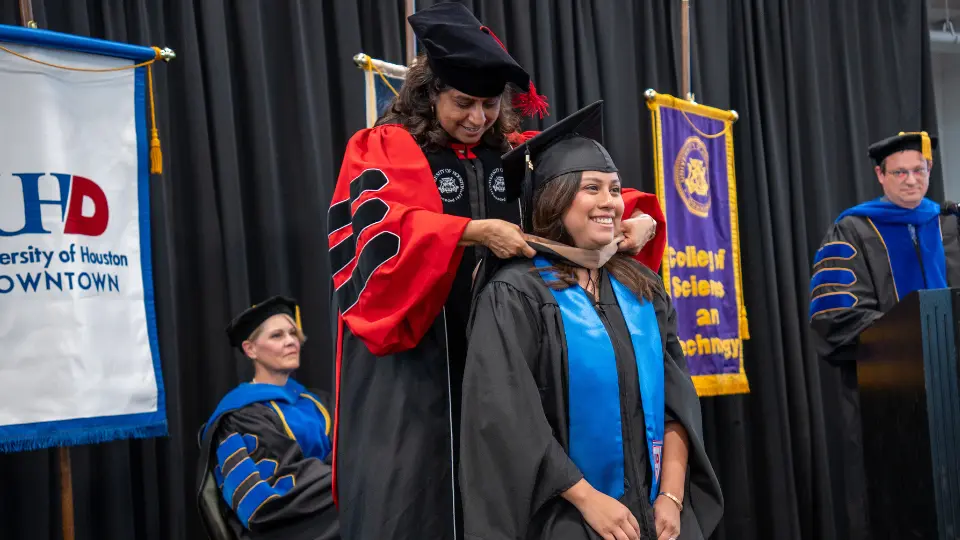 A graduate student is hooded by a faculty member at the university of houston-downtown