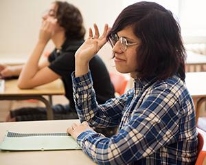 Student sitting in their desk picking up thier hands