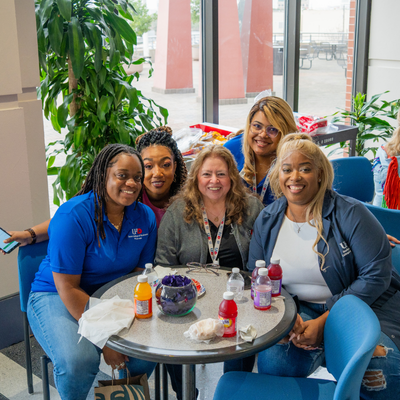 University of Houston Downtown staff sit at a table and smile 