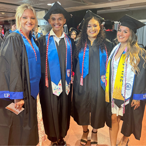Four University of Houston-Downtown students smile while wearing graduation regalia at UHD's 78th Commencement Ceremony at NRG Stadium 