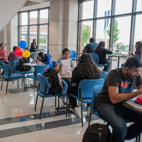 students sit at tables in the skyline lounge while eating lunch