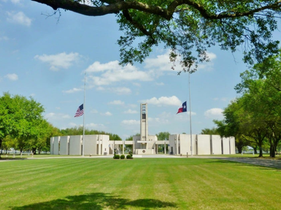 Houston national cemetery in Houston, Texas. American and Texas flags wave in the wind aside a chapel and building at the houston national cemetery.