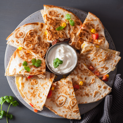 a plate of chicken quesadillas and sour cream.