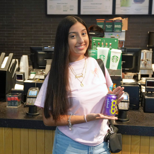 A student in a pink tshirt and jeans holds a Poppi soda at the uhd food court starbucks at the university of houston-downtown in houston, texas