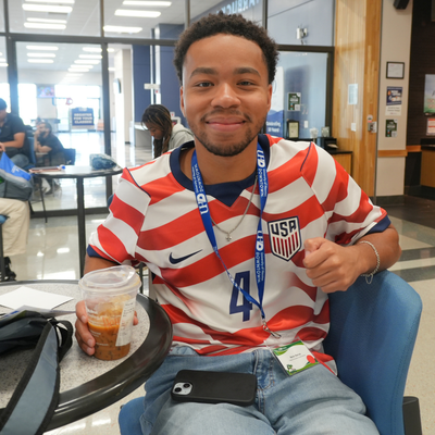 A student wears a United States soccer jersey while holding an ice coffee at the University of Houston-Downtown's food court 