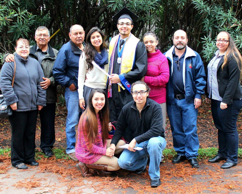 Ten members of the Valdez family smile outside. One of the members of the family wears graduation regalia from the University of Houston-Downtown. The family has five university alums. 