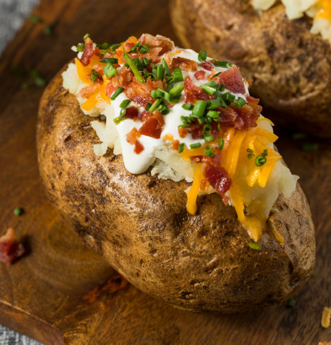 A loaded baked potato with chives, sour cream, cheese, and bacon bits.