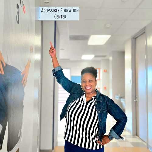 Dr. Pamplin points to the Accessible Education Center sign at the University of Houston-Downtown campus 
